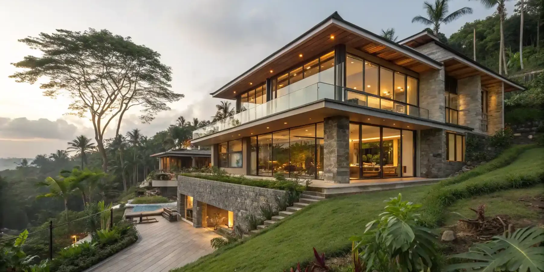A completed contemporary Balinese villa lit at dusk on a planted hillside
