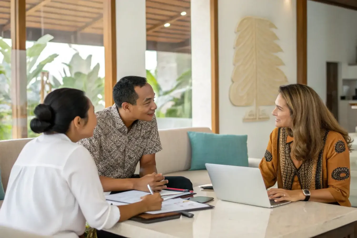 Three people in consultation around a laptop at a table in a Bali office