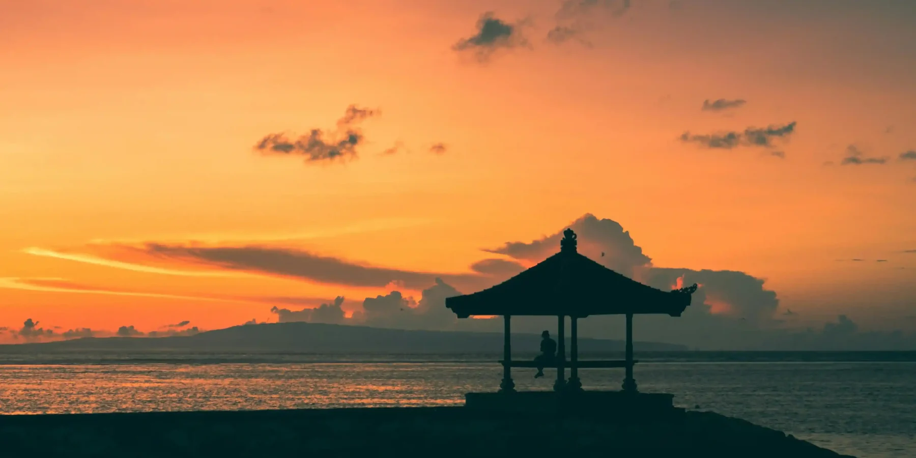 A bale silhouetted against sunrise over the water at Sanur, Denpasar