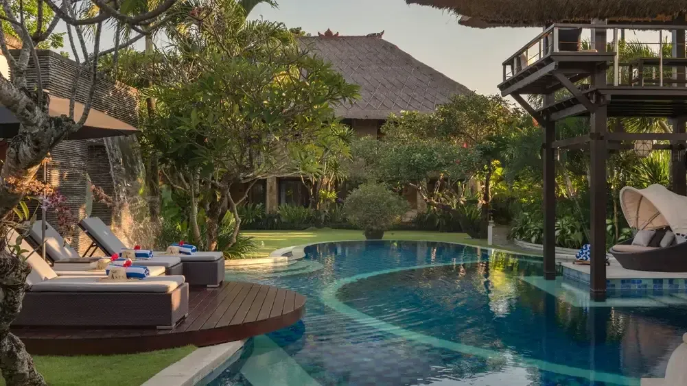 Villa pavilion with alang-alang roof beside a garden lap pool